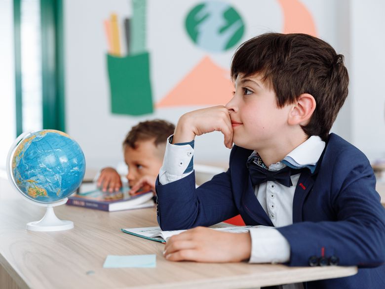 A student thinking, pencil in hand, in a bright classroom